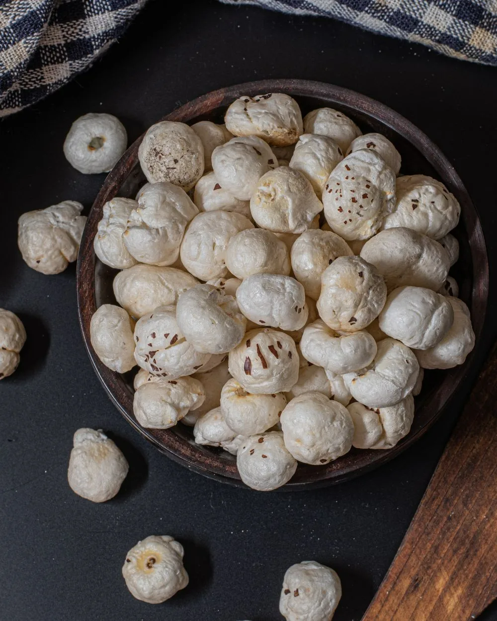 Bowl of makhana with a wooden spoon on a dark table